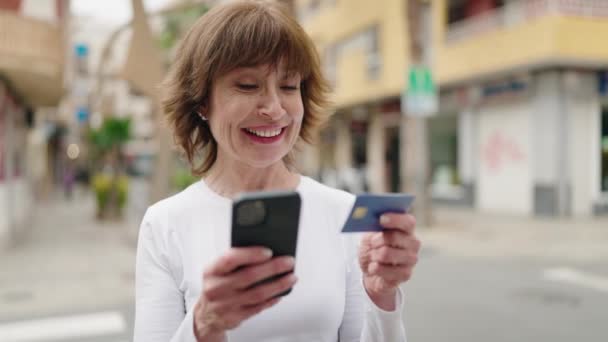 路上でスマホやクレジットカードを使っている中年女性 — ストック動画
