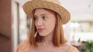 Genç, kızıl saçlı, güler yüzlü, yaz şapkası takan bir turist.