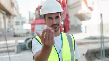 Genç İspanyol mimar gülümsüyor. Kendinden emin bir şekilde sokakta el kol hareketi yapıyor.