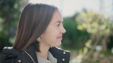 Genç, güzel, İspanyol bir kadın, gülümsüyor. Parkta kendine güveniyor.