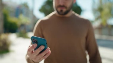Genç İspanyol adam gülümsüyor. Parktaki akıllı telefondan konuşuyor.