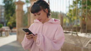Genç İspanyol kadın akıllı telefon kullanıyor. Sokakta kazanan yüz ifadesi var.