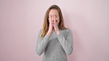 İzole edilmiş pembe arka planda sürpriz bir ifadeyle duran beyaz bir kadın.