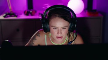 Genç sarışın kadın oyuncu oyun odasında video oyunu oynuyordu.