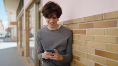 Sokakta akıllı telefon kullanan, kendine güvenen genç bir İspanyol.