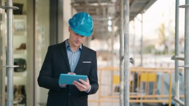 Young caucasian man architect with relaxed expression using touchpad at street