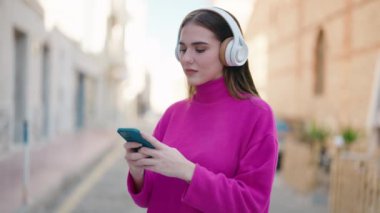 Sokakta müzik dinleyen kendine güvenen genç sarışın kadın.