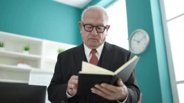 Üniversite sınıfında kıdemli öğretmen ayakta kitap okuyor.