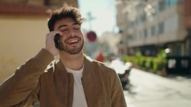 Genç İspanyol adam gülümsüyor. Kendine güveniyor. Sokakta akıllı telefondan konuşuyor.