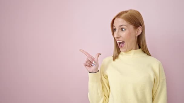 Молода Блондинка Посміхається Впевнено Вказуючи Пальцями Бік Ізольованого Рожевого Фону — стокове відео