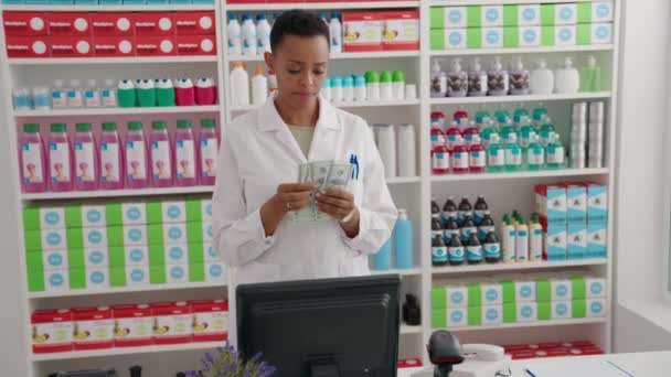 African American Woman Pharmacist Smiling Confident Counting Dollars Pharmacy — ストック動画