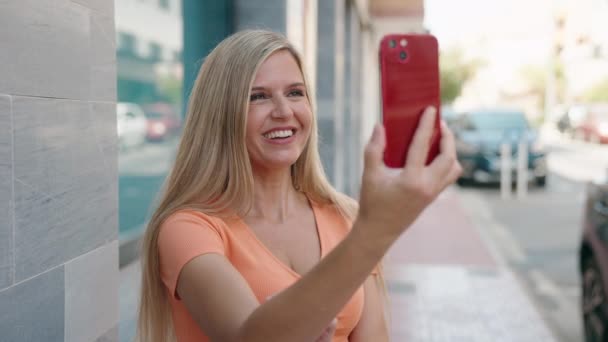 年轻的金发女人带着自信的笑容在街上打电话 — 图库视频影像