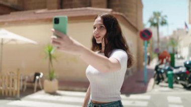 Young woman smiling confident making selfie by the smartphone at street