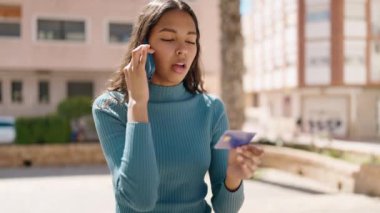 Genç Afrikalı Amerikalı kadın caddede akıllı telefondan konuşuyor.