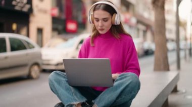 Young blonde woman listening to music and dancing at street