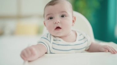 Sevimli beyaz bebek yatak odasında sandalyede oturuyor.