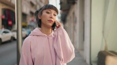 Genç İspanyol kadın gülümsüyor. Kendine güveniyor. Akıllı telefondan konuşuyor.