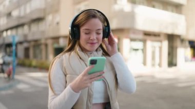 Genç sarışın kadın kendine güveniyor müzik dinliyor ve sokakta dans ediyor.