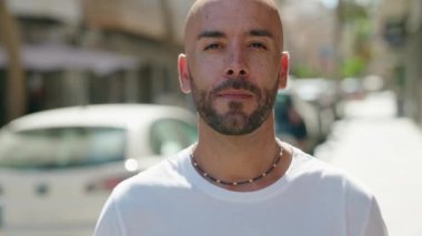 Genç kel adam gülümsüyor. Elinde 100 dolarlık banknot tutuyor.