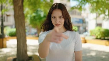 Young woman smiling confident doing coming gesture with hands at park