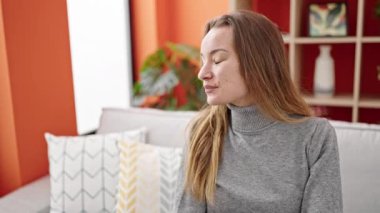 Young caucasian woman smiling confident sitting on sofa at home