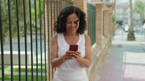 Жінка Середнього Віку Посміхається Впевнено Використовуючи Смартфон Вулиці — стокове відео