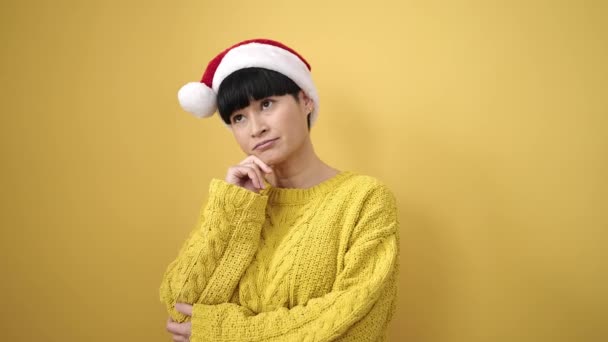 Jovem Chinesa Sorrindo Confiante Vestindo Chapéu Natal Sobre Fundo Amarelo — Vídeo de Stock