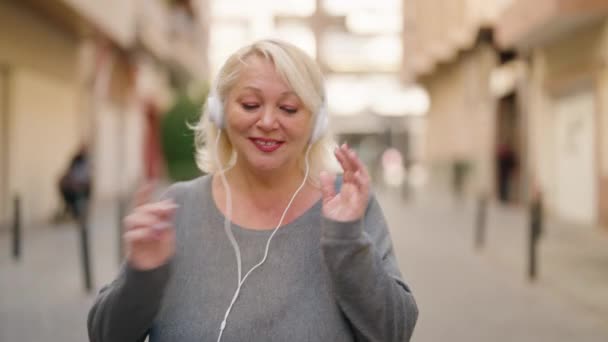 Μέση Ηλικία Ξανθιά Γυναίκα Ακούγοντας Μουσική Χρησιμοποιώντας Smartphone Και Χορεύοντας — Αρχείο Βίντεο
