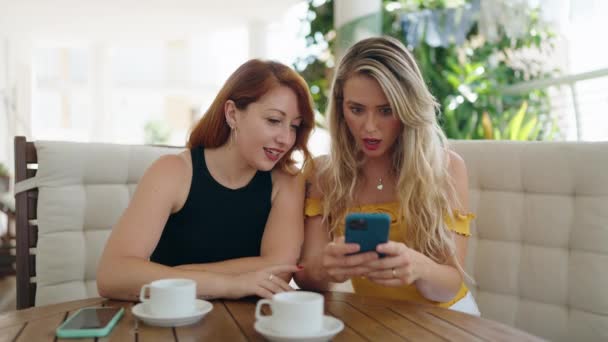 Två Kvinnor Använder Smartphone Med Överraskande Uttryck Sitter Bordet Hemma — Stockvideo