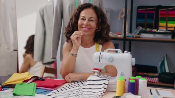 中年妇女裁缝笑着自信地坐在服装厂的桌子上 — 图库视频影像