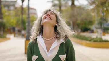 Middle age woman smiling confident looking to the sky at park