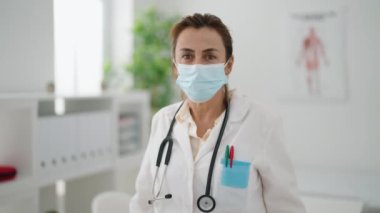 Middle age woman wearing doctor uniform standing at clinic