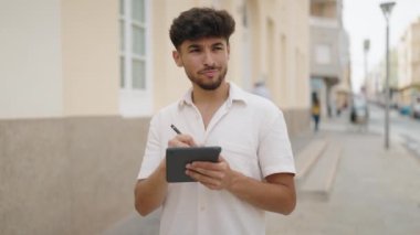 Young arab man drawing on touchpad standing at street