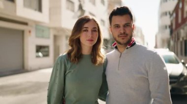 Genç çift gülümsüyor. Birbirlerine sarılıyorlar. Sokakta duruyorlar.