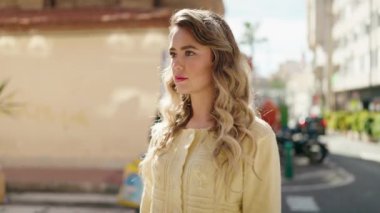 Sokakta kendine güvenen genç sarışın kadın gülümsüyor
