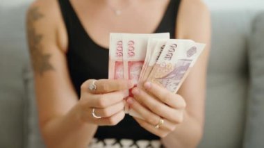 Genç bir kadın evde İzlanda Kronuru banknotlarını sayıyor.