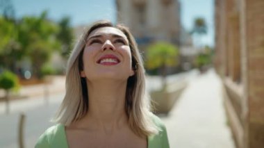 Young woman smiling confident looking to the sky at street