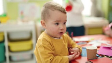 Adorable blond toddler standing with relaxed expression at kindergarten