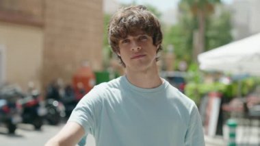 Young blond man doing negative sign with thumbs down at street