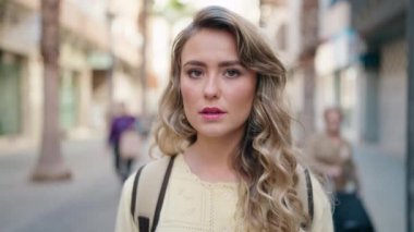 Sarışın genç bir kadın turist, rahat bir ifadeyle caddede duruyor.