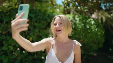 Young blonde woman smiling confident having video call at park