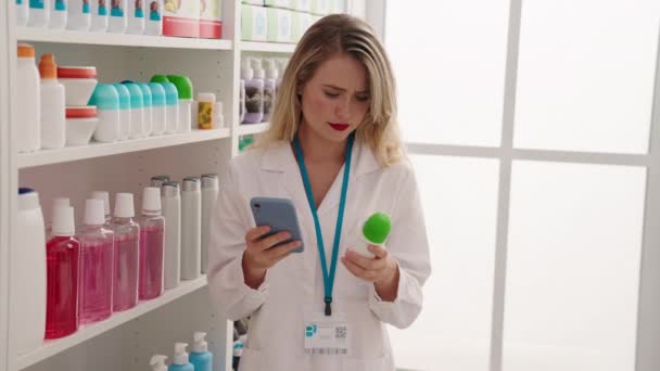 薬局でデオドラントを持つスマートフォンを使用した若い美しいヒスパニック系女性薬剤師 — ストック動画