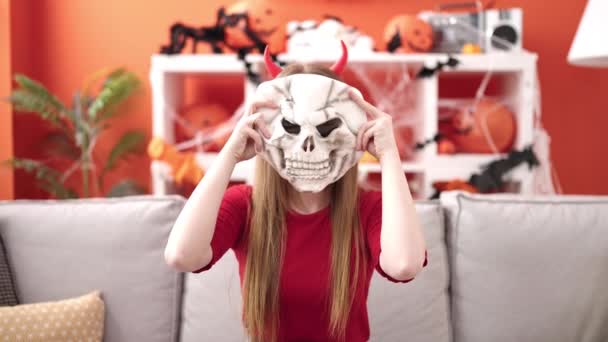 Young Blonde Woman Wearing Devil Costume Holding Skull Mask Home — Vídeos de Stock