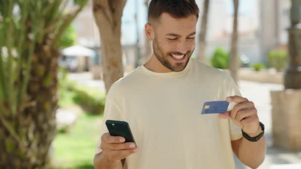 公園でスマートフォンやクレジットカードを使っている若いヒスパニック系の男 — ストック動画
