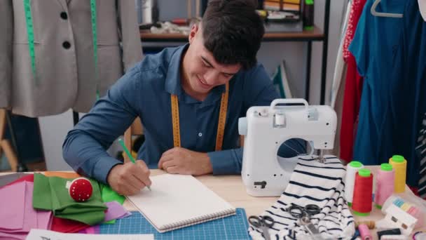 Młody Hiszpan Krawiec Uśmiechający Się Pewnie Rysując Notatniku Fabryce Odzieży — Wideo stockowe