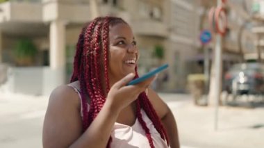 Sokakta yürürken akıllı telefondan konuşan Afrikalı Amerikalı kadın.