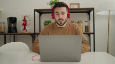 Evdeki masada oturan Latin asıllı genç adam.