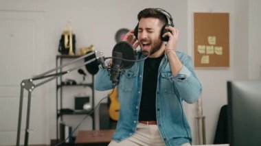 Genç İspanyol adam müzik stüdyosunda şarkı söylüyor.