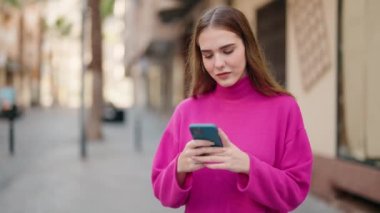 Sokakta akıllı telefon kullanan, kazanan yüzü olan genç sarışın kadın.