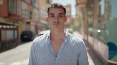 Young hispanic man smiling confident doing photo gesture with hands at street